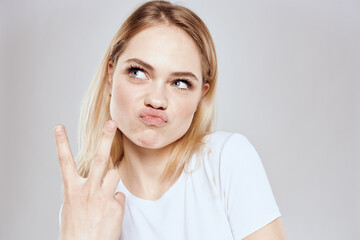 Cheerful blonde woman in white t-shirt cropped view light background