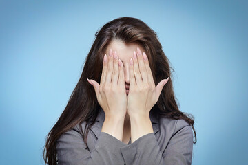 young girl covers her face with her hands