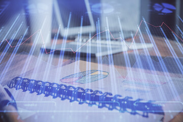 Double exposure of financial graph drawings and desk with open notebook background. Concept of forex market