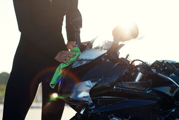 Plakat close up of seductive young woman's hand washing stylish sport motorcycle and wipes it from pink foam at sunrise.