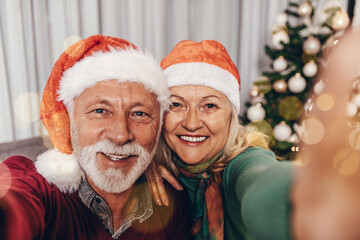 Happy senior couple celebrating New Year at their home and taking selfie photo.