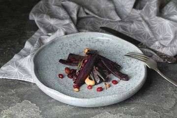 Tasty baked black carrot on grey table, closeup