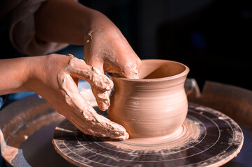 Fototapeta na wymiar Craftsman's hands and potter's wheel. Close-up.