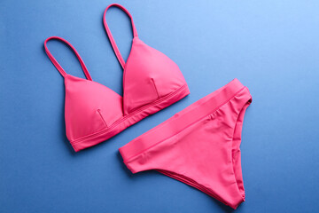 Beautiful pink bikini on blue background, top view