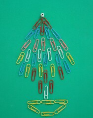 Figura de pino navideño hecho con clips de colores sobre superficie verde 4