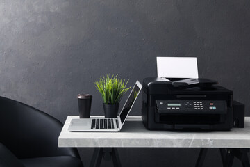 New modern printer, laptop and cup of drink on grey table indoors - obrazy, fototapety, plakaty