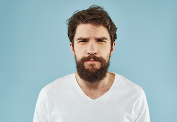 Handsome man with a beard on a blue background white t-shirt portrait