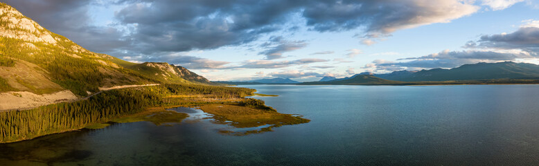 Fototapeta na wymiar Gorgeous Panoramic View of Scenic Lake by Golden Moutain and Forest at Sunset in Canadian Nature. Aerial Drone Shot. Taken near Atlin, Yukon, Canada.