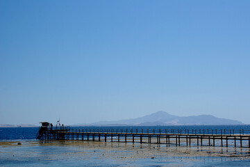 Fototapeta na wymiar Island Pier Distant Seashore Shoreline