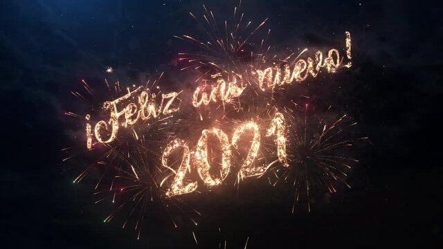 2021 Happy New Year greeting text in Spanish with particles and sparks on black night sky with colored slow motion fireworks on background, beautiful typography magic design.