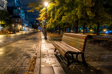 Banc sur la rue de la Commune, de nuit,  devant le marché Bonsecours à Montréal après la pluie.