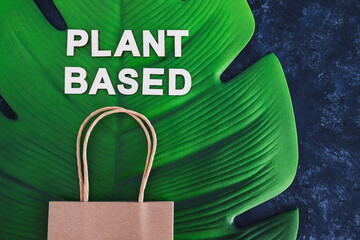 choices for the environment, plant-based text with shopping bag on big tropical leaf on dark background