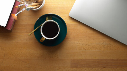 Wooden table with coffee cup, closed laptop, stationery and copy space