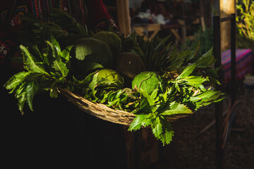 Green wool along with vegetables in a basket held by a woman in chincheros