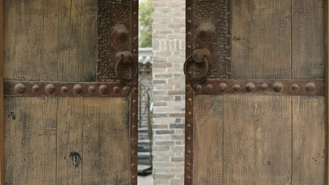 Old rustic wooden door with metal ring handles, the process of opening