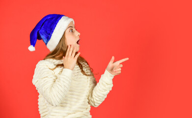 Christmas holiday invitation. Adorable girl wear santa claus hat red background. Emotional face expression. Happy childhood. Counting days till christmas. Christmas party. Can not hold back emotions