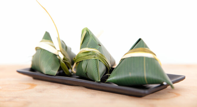 Three freshly wrapped zongzi on the cutting board