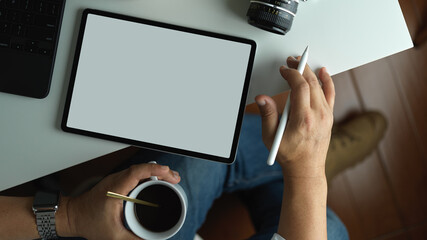 Fototapeta na wymiar Man working on blank screen tablet while drinking coffee cup, include clipping path