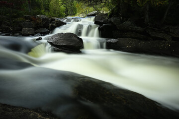 waterfall in the forest flowing around a stone. Long exposition of the cascade. Chute dans les bois sur la rivi&egrave;re Noire Longue exposition. Portneuf, QC. Canada