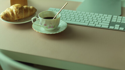 Breakfast meal with coffee cup and croissant  on computer table