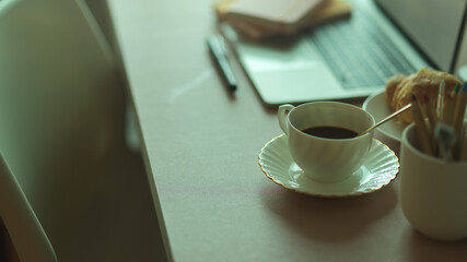 Side view of breakfast meal with coffee cup and croissant on workspace