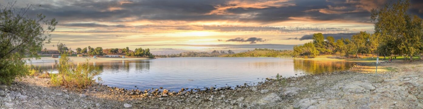 a breathtaking panoramic shot of the still blue waters and lush green trees and majestic mountain ranges at Frank G Bonelli Regional Park at Puddingstone Lake in San Dimas California USA