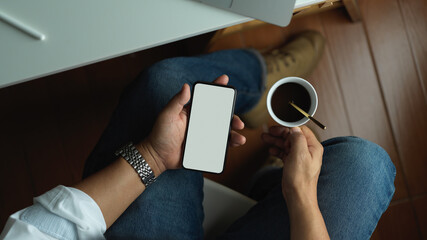 Man using mock up blank screen smartphone and holding coffee cup