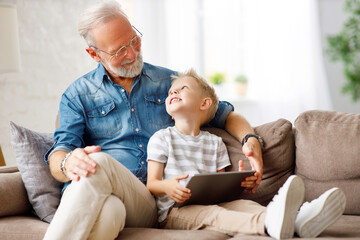 Obraz premium Grandfather and grandson using tablet on sofa