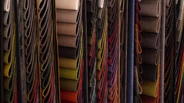 Various Fabrics Hang in Multiple Colors and Patters off a Wall, Camera Track Right