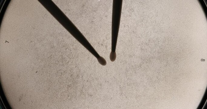 : Close up top down view slow motion drumroll over backlit snare head.