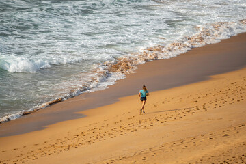 lady jogger running along the sand at the beach, getting fit