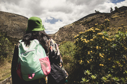 Turista de espaldas camino a Millpu con vegetaci&oacute;n y flores amarillas