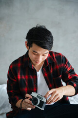 Fototapeta premium Asian man checking film camera before going outside.