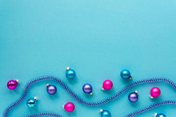Christmas or new year composition with multicolored balls and tinsel on a blue background. Space for text
