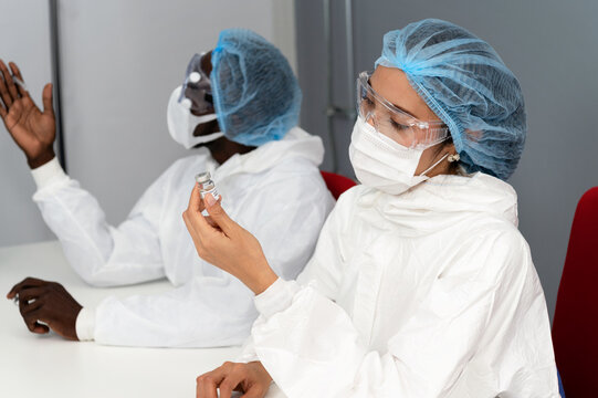 Diversity coronavirus covid 19 disease experts discuss in a clean laboratory meeting room on coronavirus covid 19 vaccine sample labelled coronavirus covid 19 with protective suit, mask and gloves