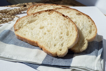  Three pieces of wheat bread on a kitchen towel. Wheat ears are near.