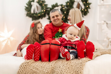 Christmas and new year. A happy family sitting on the bed in the same socks. Waiting for a Christmas miracle