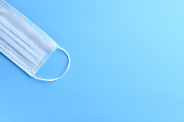 Medical mask on a blue medical background, empty space for text on the right. Concept of the protection against coronavirus, 2019-nCoV.