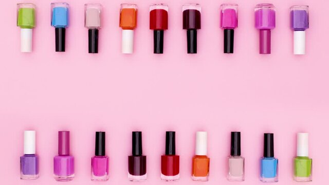 Nail polish bottles changing colors on top and bottom of pastel pink theme. Stop motion