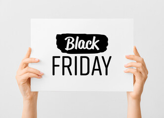 Female hands holding card with text BLACK FRIDAY on light background