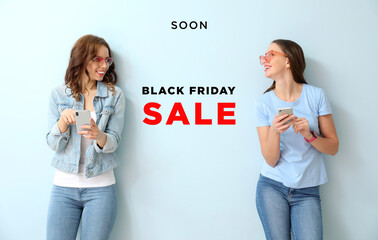 Young women with mobile phones on color background. Black Friday sale