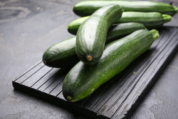 Board with fresh zucchini squashes on dark background
