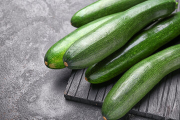 Board with fresh zucchini squashes on dark background