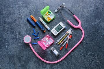 Glucometer, stethoscope, lancet pen, pills, insulin and syringes on dark background. Diabetes concept