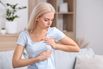 Young woman checking her breast at home. Cancer awareness concept