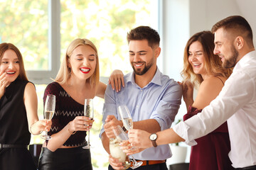 Young people drinking tasty champagne at party in office
