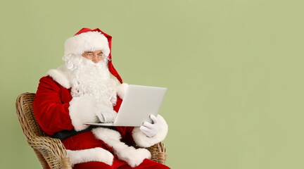 Santa Claus with laptop on color background