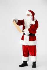 Santa Claus reading letter on light background