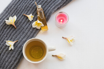 Obraz na płótnie Canvas natural herbal oils from flower frangipani smells scents aroma with hot honey lemon tea healthy drinks and knitting wool scarf of lifestyle woman relax winter season on background white