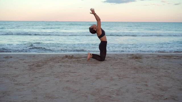 Woman practice yoga at beach shore at sunset waves in the background. Upward bow pose, plank pose, warrior pose and mountain pose. Eka pada Urdhva dhanurasana, Vasistasana, Virabhadrasana, tadasana.